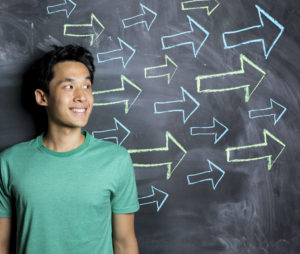 student standing in front of chalkboard with arrows drawn in chalk