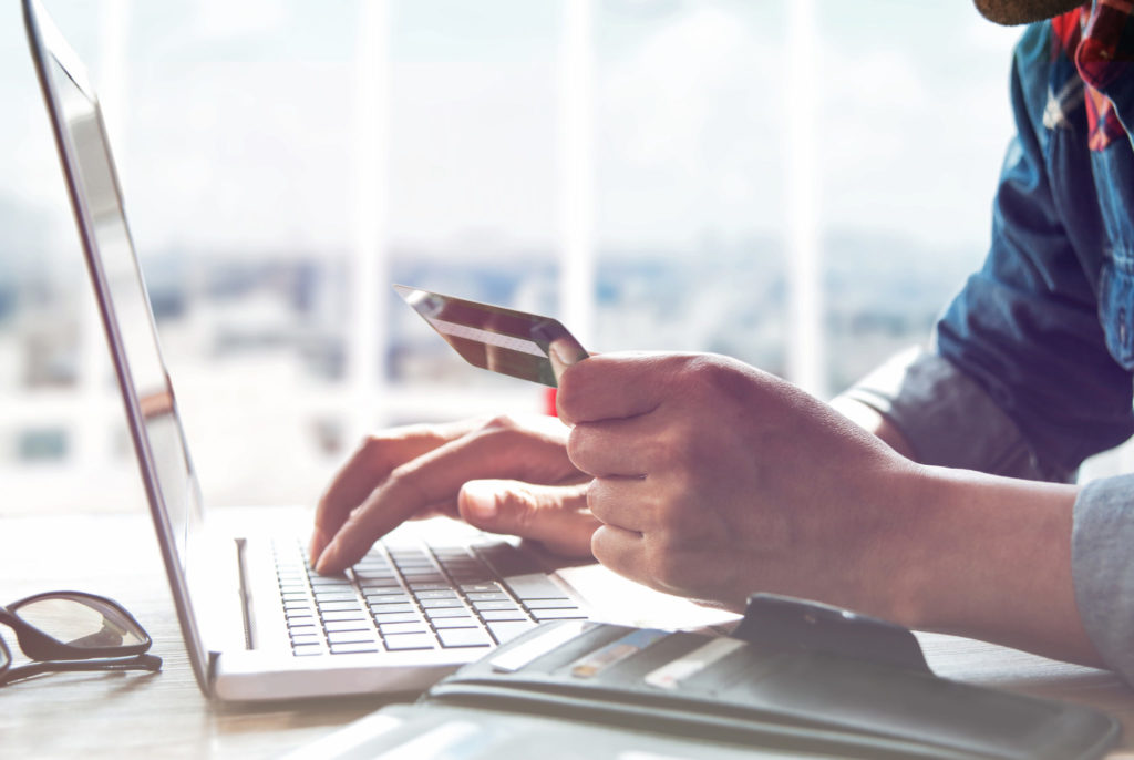 Hands holding credit card and using laptop.