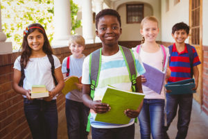 Portrait of diverse group of smiling young students in school corridor