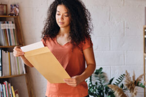 a girl reading a piece of paper she received in a large manila envelope.