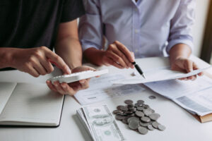 two people comparing numbers between a calculator and a piece of paper.