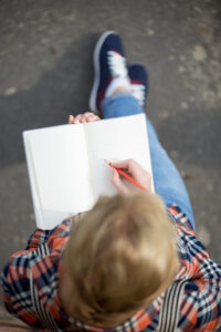 a teen writing things down in a notebook.