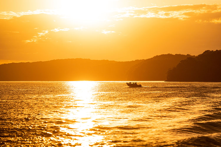 A sunny day at the lake of the Ozarks with a boat cruising over the water.