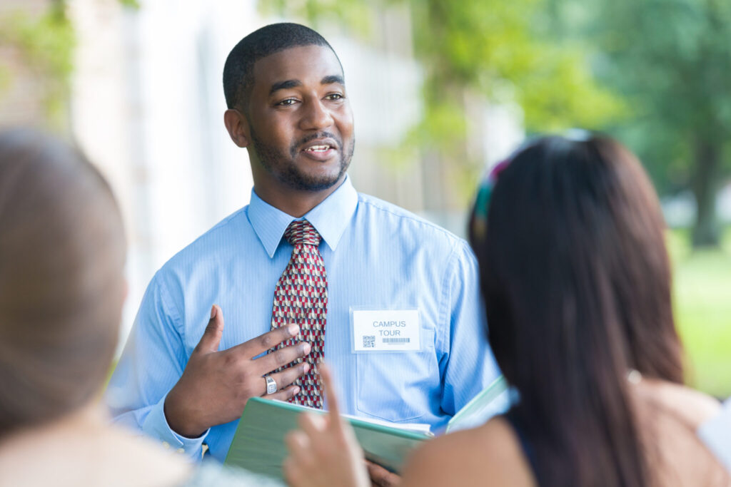 A campus tour guide giving high school students a tour of the college campus.