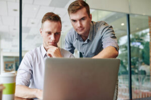 Two people staring at the screen of a laptop.