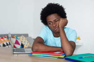 Unmotivated african american male student at desk