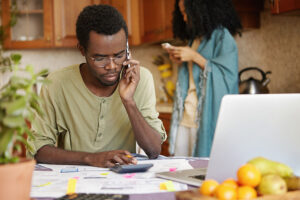 A concerned african-american man looking through financial documents.