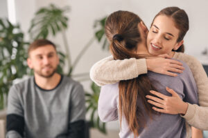 A woman comforting her friend with a hug.