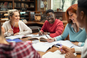 A group of students sitting around a table having fun while studying together.