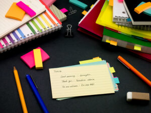 A pile of flashcards surrounded by other study material like notebooks, pens, and sticky notes. The flashcards are helping to learn Turkish.