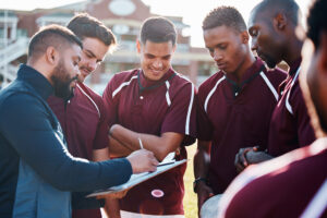 a rugby team with their coach showing them a play to use.