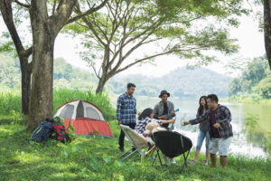 Group of friends hanging out beside a lake and enjoying camping .