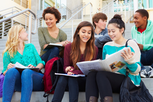 a group of teenagers sharing class notes on the staircase