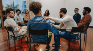 A therapy group in a circle comforting someone.