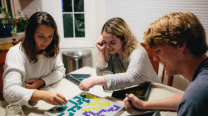 three friends laughing while playing a strategy board game